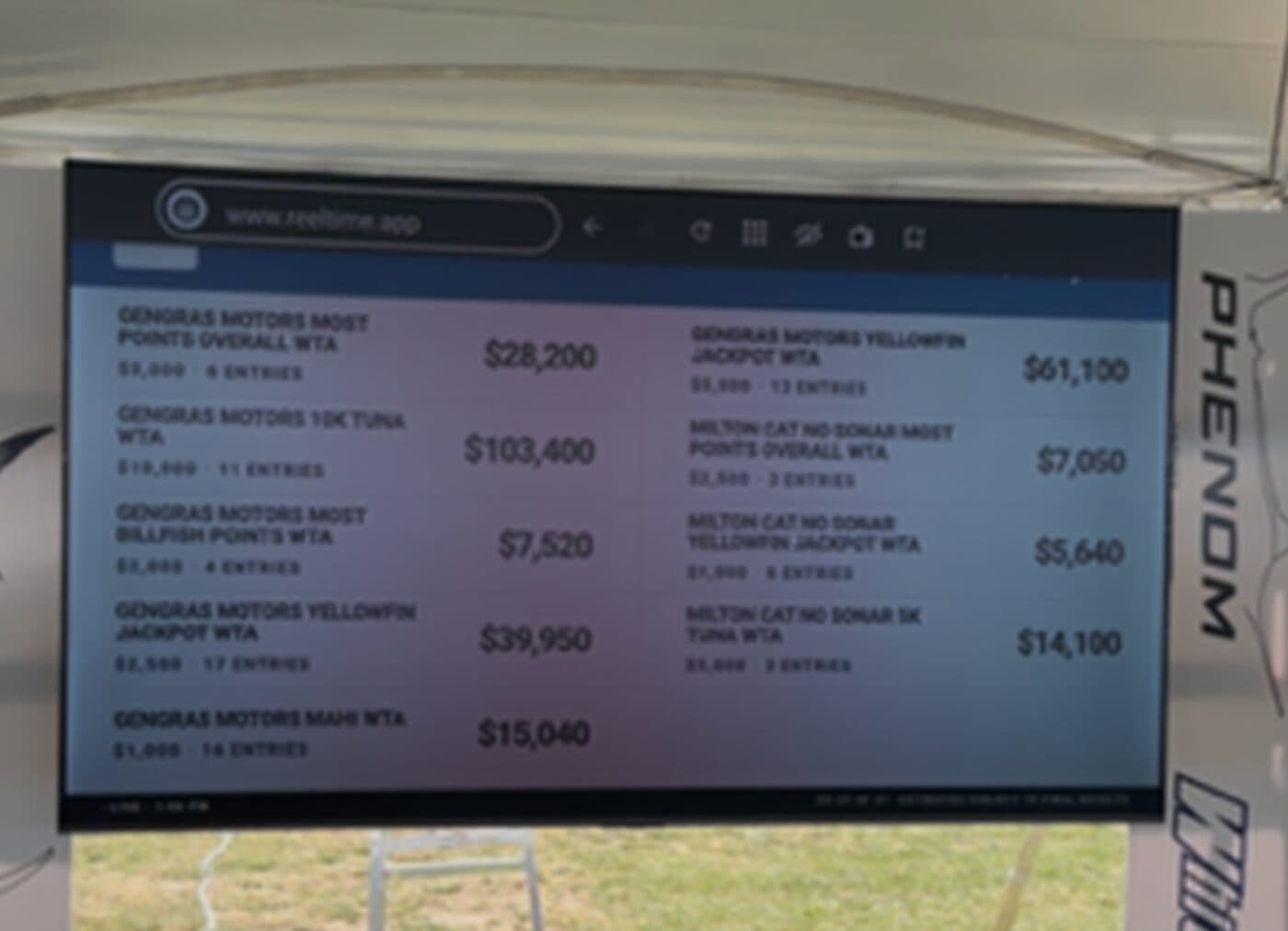 A large TV under an event tent showing live tournament jackpot payouts